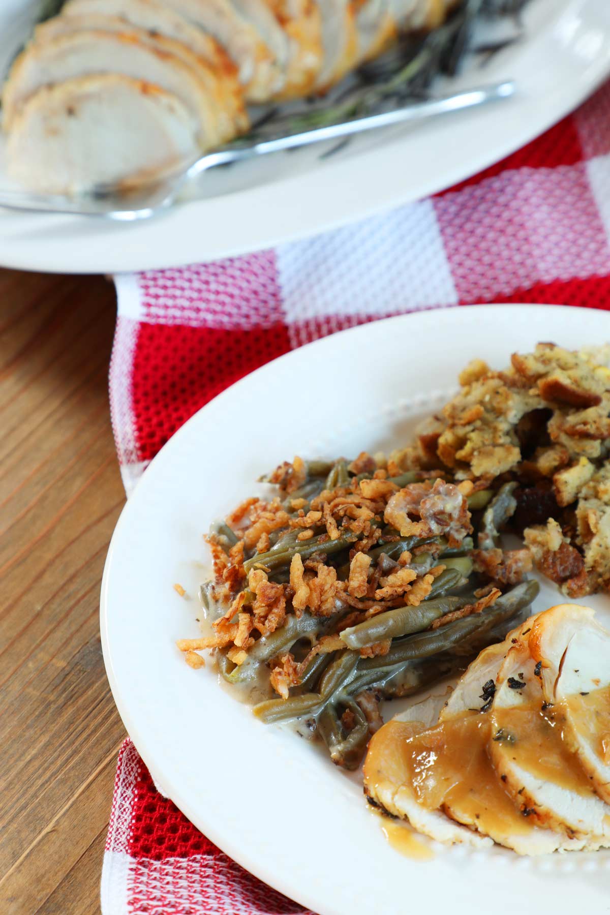 Green Bean Casserole on a white plate with turkey and stuffing.