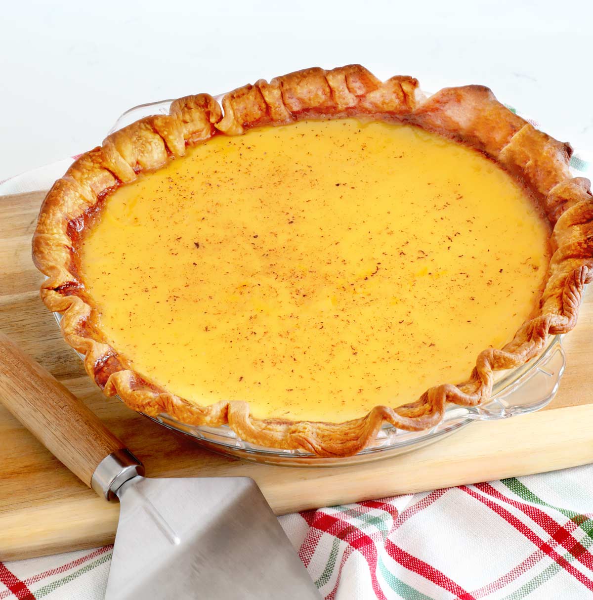 Eggnog pie on a wooden cutting board with a pie server.